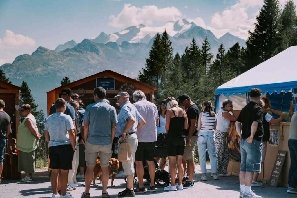 Menschen stehen in einer Schlange vor Marktständen auf dem Moosalp Markt 2025, um regionale Spezialitäten zu entdecken.